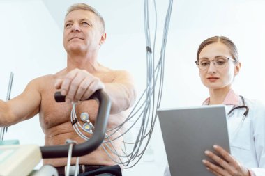 Hastanın stres EKG 'si sırasında tablet bilgisayara not alan doktor.