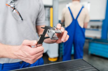 İşçiler endüstriyel kullanım için metalden imal edilmiş bir ürünün kalitesini tartışıyorlar