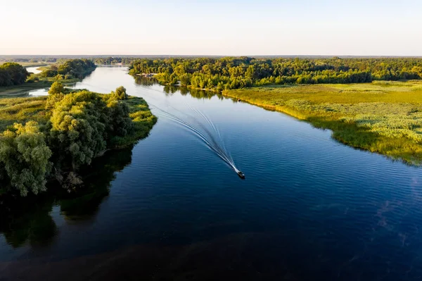 ウクライナのCherkasy近くの穏やかな水の上にモーターボートとトレイルを持つドニエプル川への空中朝の景色 ストック画像