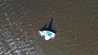 Small yacht and lonely yachtsmen on lake water in wind, aerial view