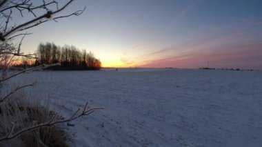 Karlı tarlaların üzerinde kış ortası gün doğumu, zaman aşımı