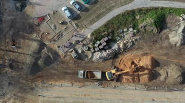 Bir kazıcı kasaba meydanındaki kamyona toprak yüklüyor.