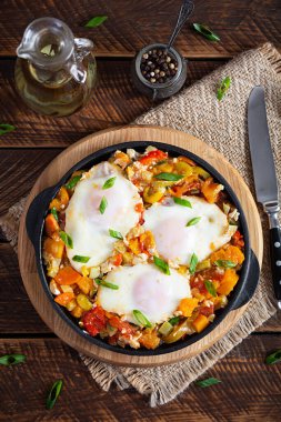 Kızartma tavasında Shakshouka. Sebzeli yumurta, domates, biber, balkabağı ve soğan. Üst görünüm
