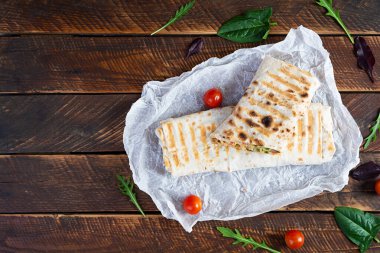 Tahta arka planda salata ve peynirli lezzetli tavuklu shawarma sandviçi
