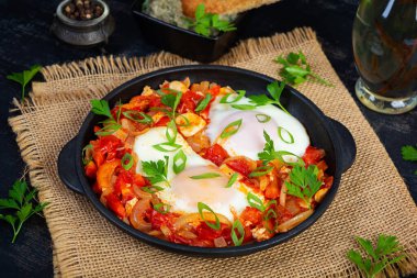 Izgara ekmekli Shakshuka. Domates, biber, sarımsak ve bitkilerle kızarmış yumurta.