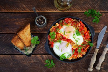 Izgara ekmekli Shakshuka. Domates, biber, sarımsak ve bitkilerle kızarmış yumurta.
