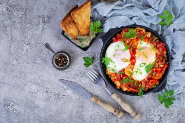 Izgara ekmekli Shakshuka. Domates, biber, sarımsak ve bitkilerle kızarmış yumurta.