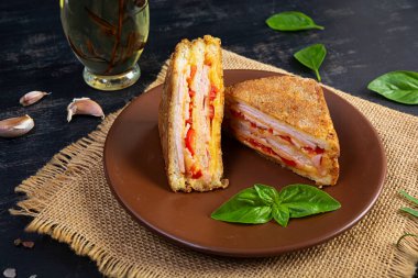 Jambon, peynir ve domatesli ekmek kırıntılarında kızartılmış sandviçler.