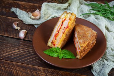 Jambon, peynir ve domatesli ekmek kırıntılarında kızartılmış sandviçler.