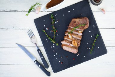 Biftek ızgara, otlu ve baharatlı taş tabakta.