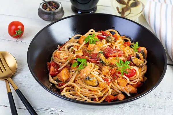 Seafood pasta with clams, salmon and tomatoes. Spaghetti with seafood cocktail