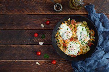 Shakshuka kızartma tavasında. Domates, biber, kabak ve otlu sahanda yumurta.