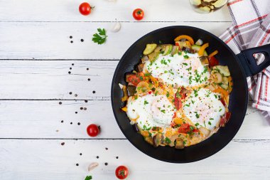 Shakshuka kızartma tavasında. Domates, biber, kabak ve otlu sahanda yumurta.
