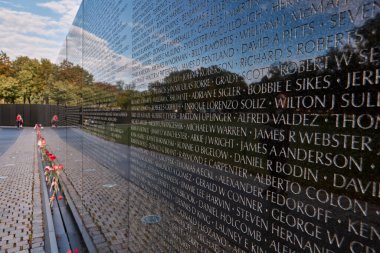 Washington DC, ABD - 3 Ekim 2016: Washington D.C. 'deki Vietnam Gazileri Anıtı' nda granite kazınmış isimler yer alıyor. Çiçekler, sakin bir çevrede ölen askerleri onurlandırır..