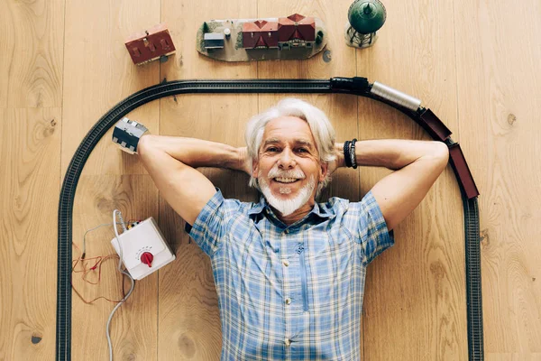 部屋でモデル蒸気機関車で遊んでいる高齢者の屋内肖像画 — ストック写真