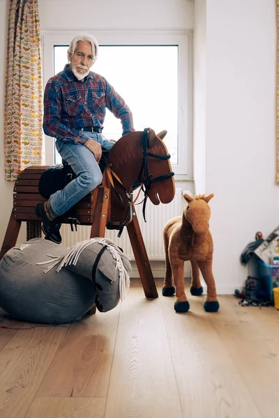 Retrato Interno Homem Idoso Jogando Cowboy Sala Netos Sentado Cavalo Fotos De Bancos De Imagens