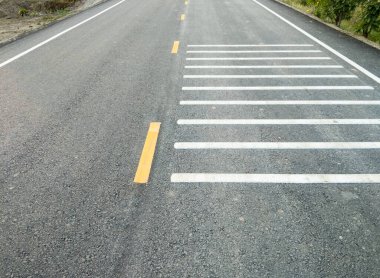 Asfalt yolda asfalt yolda, kırsal köydeki kavşağa ulaşmadan önce sürücünün dikkatini çekmek için gürültülü bir gürültüye neden olan beyaz çapraz ses şeritleri var..