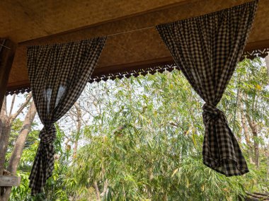 Ekose perdeler ahşap evin terasında asılı, fotokopi alanının önünde. .