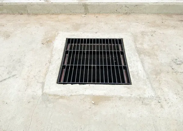 The drain cover grate on the concrete street for the drainage system near the new train station is under construction, front view with the copy space.