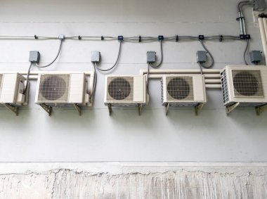 Klima sisteminin kompresör ünitesi şehir raylı istasyonunun arkasındaki beyaz duvarda asılı..