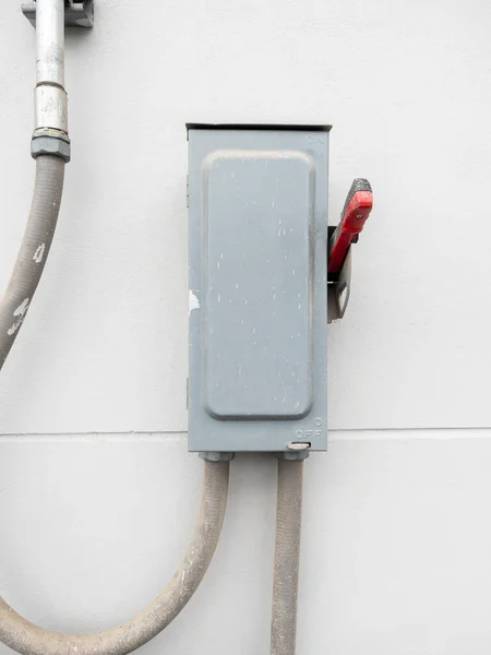 The temporary breaker on the white concrete wall of the electrical control building for use in the construction site, front view for the copy space.