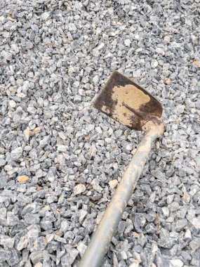 İnşaat alanının yakınındaki çimentoyu karıştırmak için taş yığınının üzerinde metal saplı eski çapa, fotokopi alanı ile ön görüş..