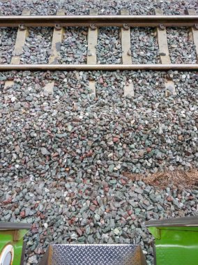 Demiryolu raylarının çarpıcı görüntüsü bir tren merdiveninden, kum, çelik ve metalin kumlu dokusunu bir sanayi sahnesinde yakalıyor..