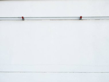 Beyaz bir fabrika duvarındaki iletişim kabloları için çelik kanal boruları endüstriyel kablolar gösteriyor. Mühendislik, imalat ve altyapı hisse senedi imgeleri için harika..