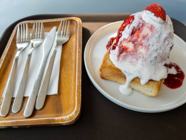 Kızarmış ekmeğin üzerinde karşı konulmaz çilek kremalı bingsu, çatal ve bıçakla servis edilmiş, kafe menüleri, yemek blogları veya stok fotoğrafları için ideal. Taze, kremalı ve iştah açıcı. Her yemek sahnesi için mükemmel..