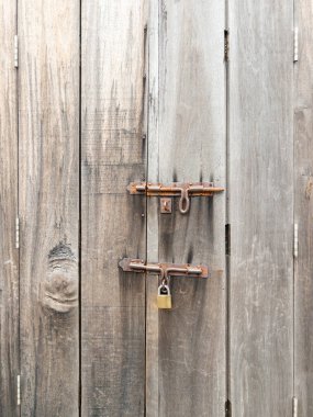 Bu resimde eskimiş ahşap kapı mandalları ve menteşeleri olan paslı bir asma kilit var. Kırsal dokuyu ve klasik cazibeyi ön plana çıkarıyor. Çiftlik evi, ahır veya güvenlik temalı tasarımlarda depo fotoğrafları için mükemmel..