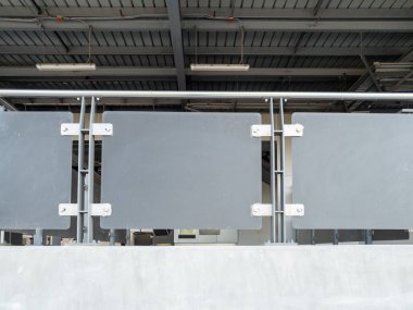 Sleek gray metal balustrade with reinforced panels and steel supports in a railway station entrance hall, under an industrial ceiling with lights, showcasing modern safety design for urban commuters.