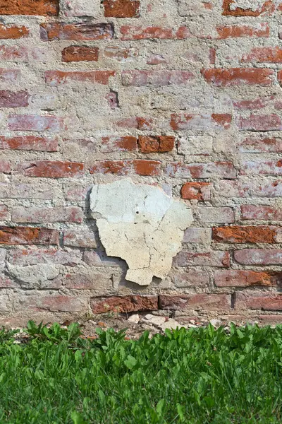 石膏と草の部分が付いている古い煉瓦の壁 ストック写真