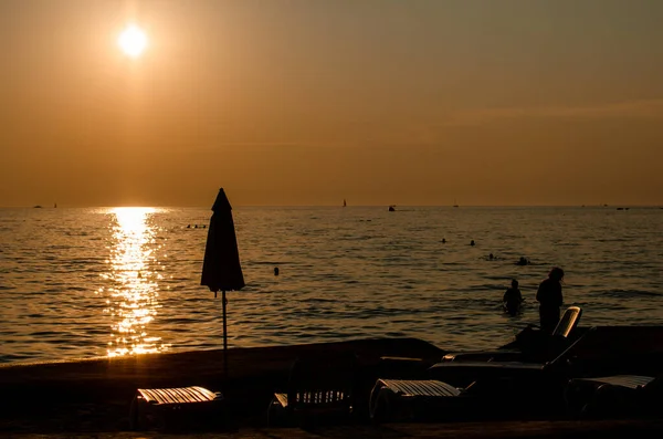 Sunset Beach Umag Croatia Silhouettes Umbrellas Sunbeds Some Swimmers Can — Stock Photo, Image