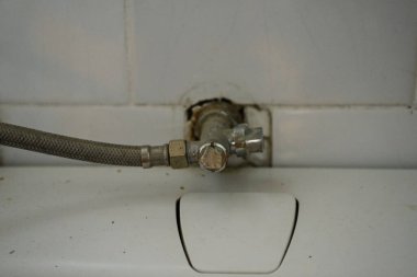 Kapakçıklı eski tesisatlar, su girişi ve banyodaki kırmızı ve beyaz fayanslı priz.