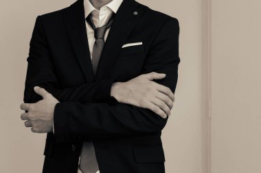 Koyu renk ceket, açık renk kravat ve beyaz gömlek bir erkeğin altın broşla resmi kombinasyonu.