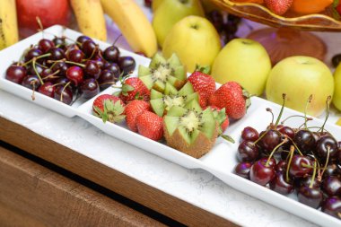 Çilek, Kivi, kiraz, elma dikkatle servis edilmeye hazır meyveler.