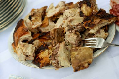 Fresh roast lamb cut into cubes and served on a plate on a table with a white tablecloth clipart