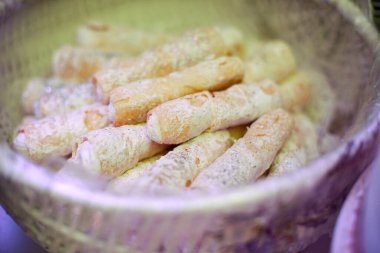 Peynirle doldurulmuş ve pudra şekeri serpiştirilmiş lezzetli börekler. Bir sepetin içinde servis edildiler. Kapat.