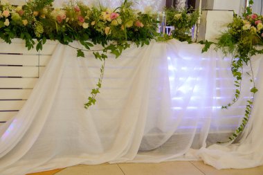 Açık pembe ve sarı güller yapraklar ve yapraklar ağaçlarda cam kaselerde beyaz mumlar ve düğün masasının süsü olarak beyaz tüller