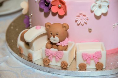 Üzerinde küçük kahverengi bir ayı olan pembe, beyaz ve mor çiçeklerle süslenmiş iki katlı pembe bir pasta ve ortasında Kiril alfabesiyle yazılmış kadın adı Daria..