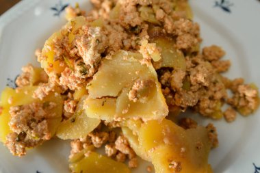 Musakka, bir tabak patates ve masada beyaz bir tabakta kıyma.