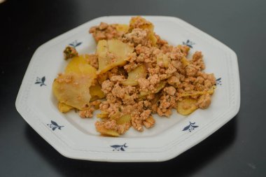 Musakka, bir tabak patates ve masada beyaz bir tabakta kıyma.