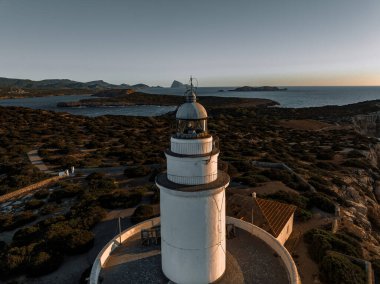 Akdeniz 'e bakan uzun bir uçurumun üzerindeki gün batımında deniz feneri.