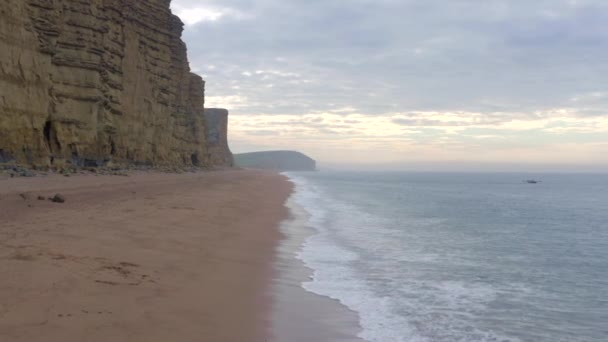 背の高い砂岩の崖がある西湾のビーチ次にイギリスの海 — ストック動画