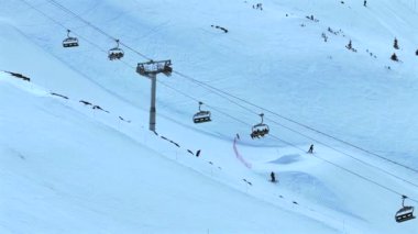 Kayakçılar ve Snowboardcular bir dağı yükseltmek için teleferik kullanıyorlar.