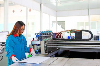 TANGSHAN CITY - MAY 28: Women worker operating large-scale inkjet printing machine in a production workshop, on may 28, 2014, Tangshan city, Hebei Province, Chin