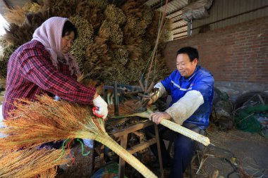 Luannan County - December 21, 2017: worker processing whisk broom in a hand workshop, Luannan County, Hebei Province, China. This is the most important traditional handicraft industry in the local area