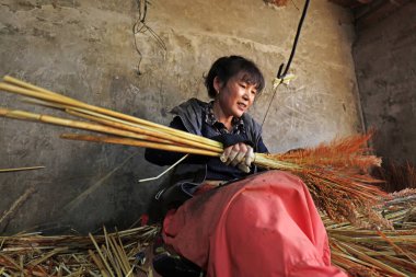 Luannan County - December 21, 2017: worker processing whisk broom in a hand workshop, Luannan County, Hebei Province, China. This is the most important traditional handicraft industry in the local area