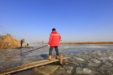 Luannan County - January 26, 2018: farmers use poles to move ice in the field, Luannan, Hebei, Chin