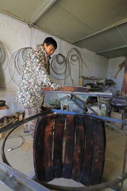 Luannan County - February 6, 2018: craftsman is working on the side board of the wooden drum in workshops, Luannan, Hebei, Chin